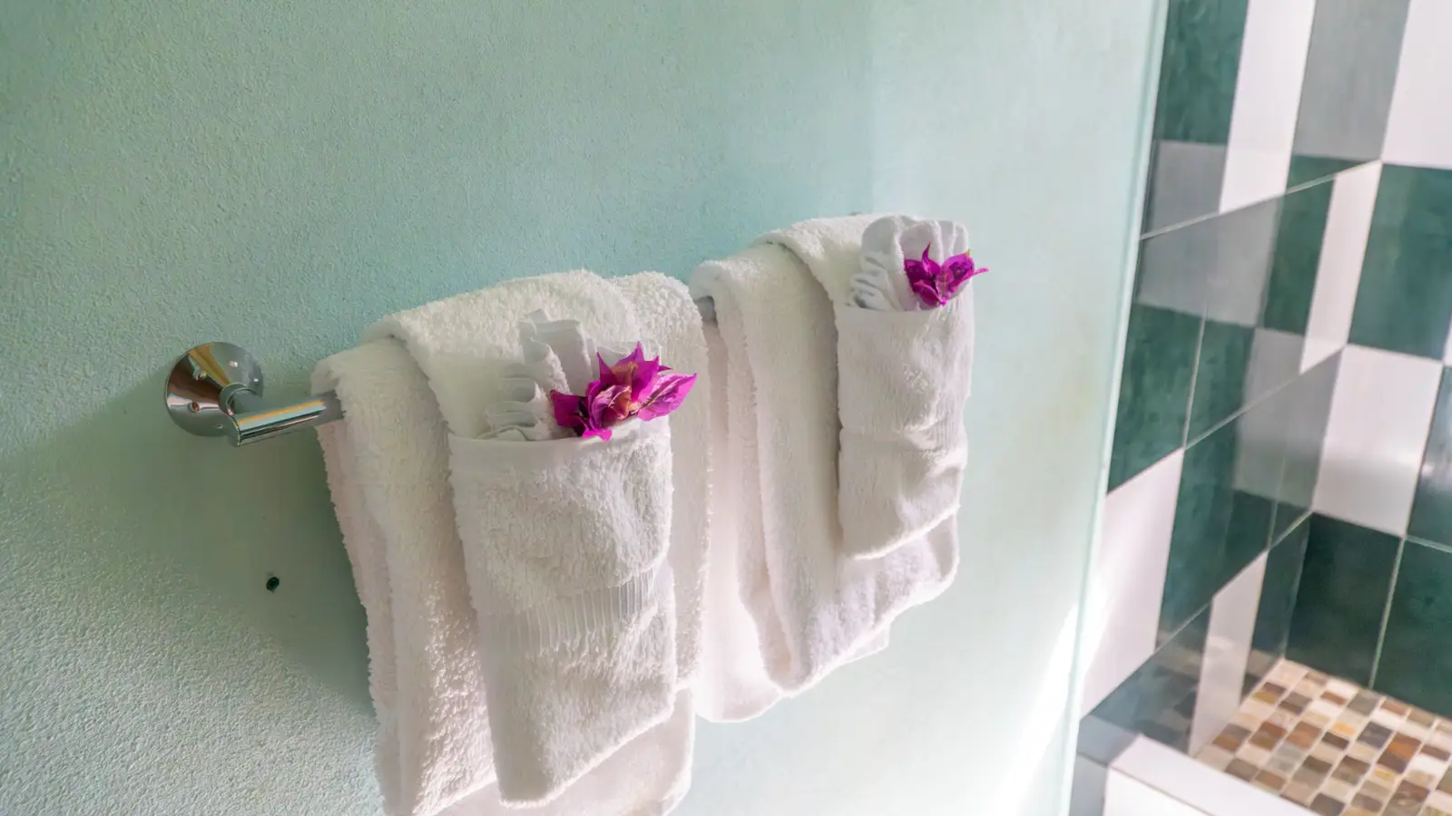 Fresh towels with bougainvillea in a bathroom at LambLion Apartments in central Antigua
