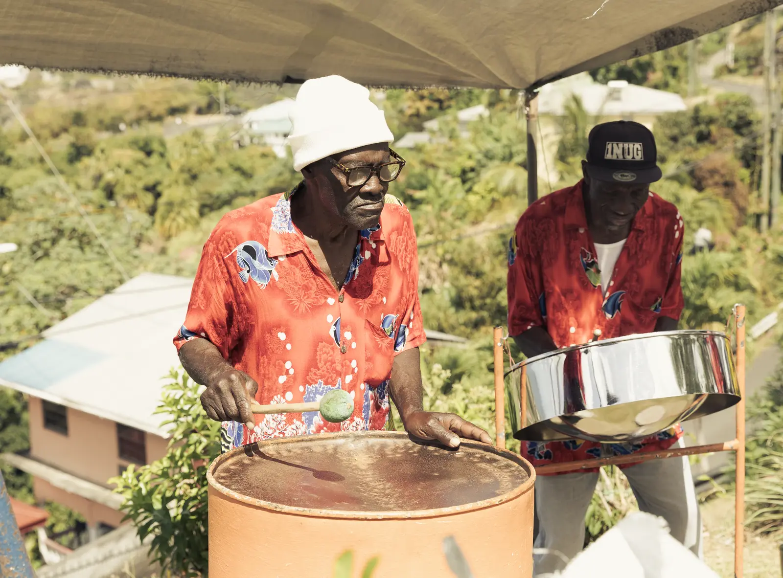 Two steel pan players performing outdoors in the Caribbean
