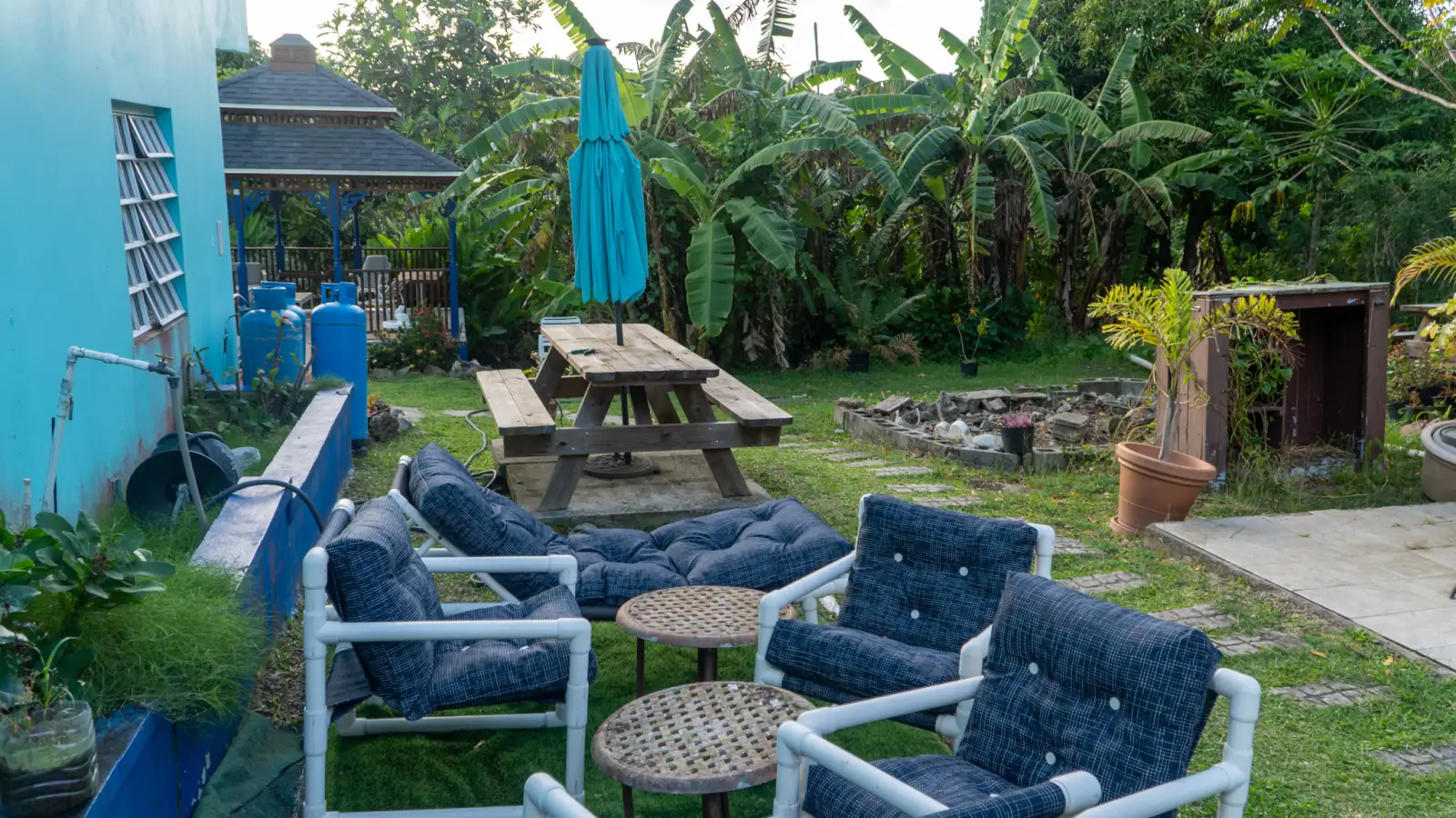 Garden seating and picnic table under banana plants at LambLion Apartments, central Antigua