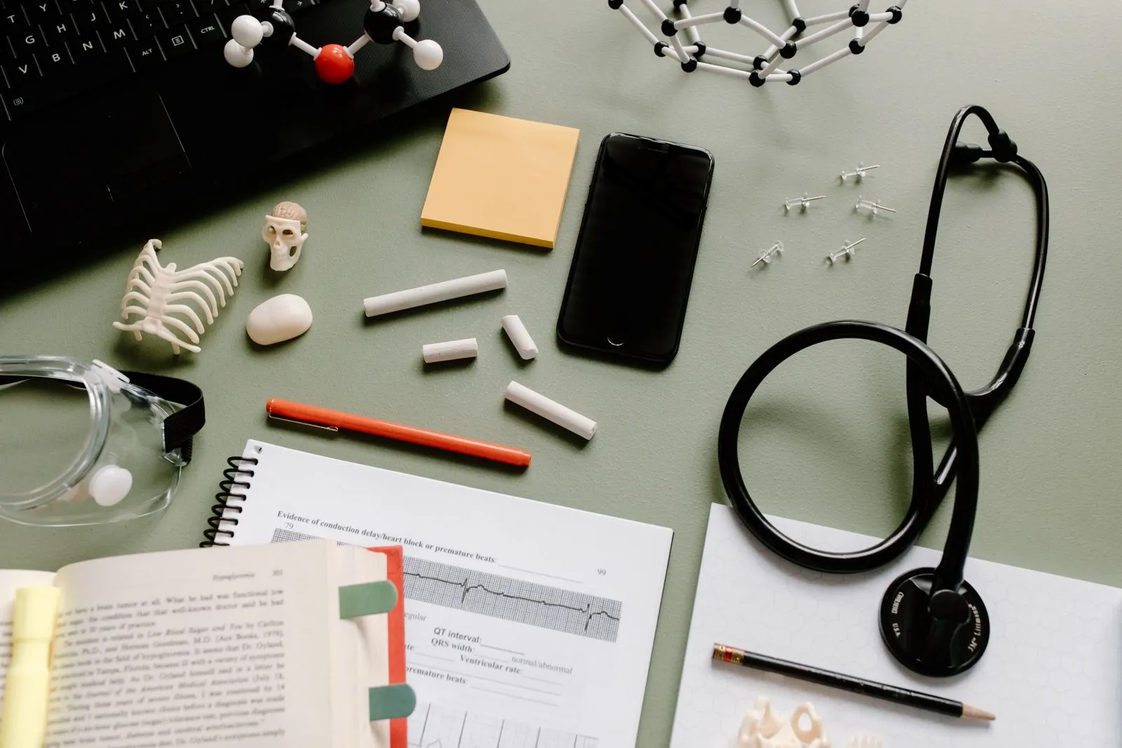 Medical study desk with a stethoscope, notes and anatomy models