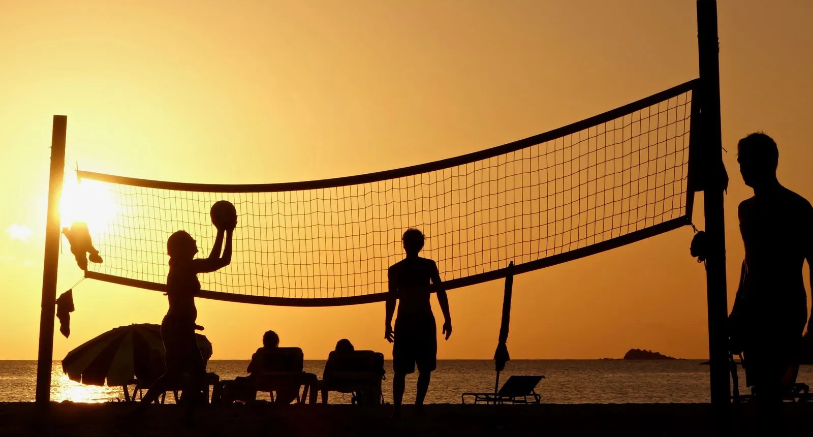 People playing beach volleyball at sunset on a beach in Antigua