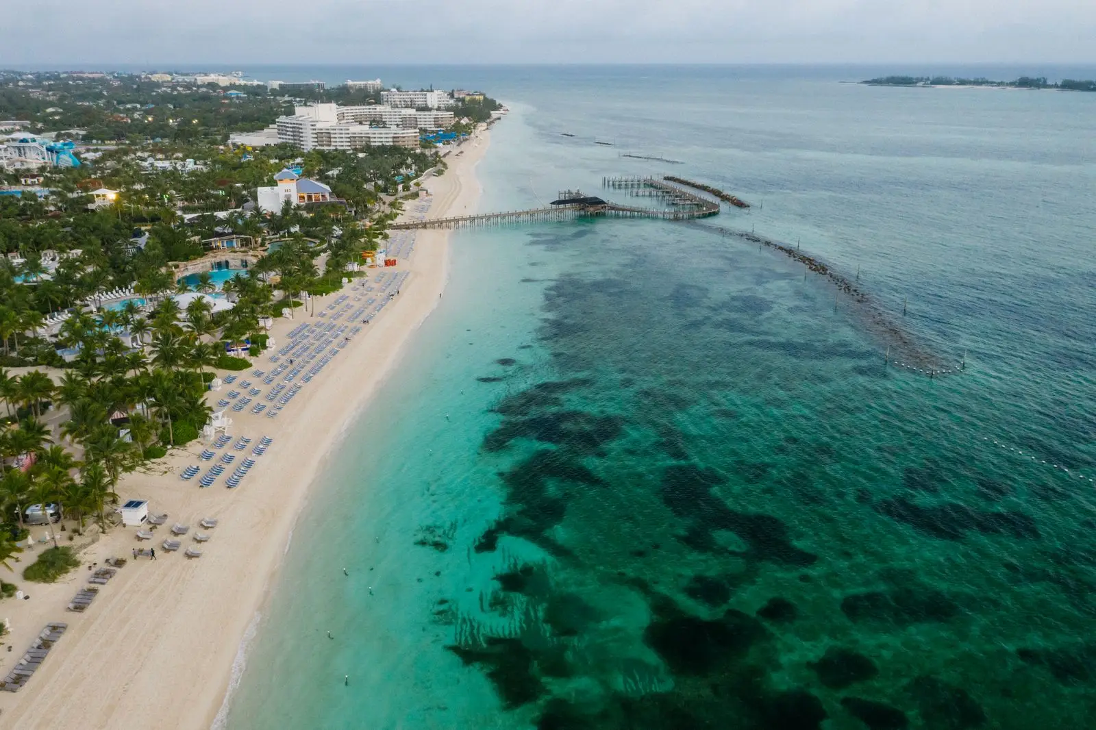 Aerial view of a beachfront resort strip and pier on turquoise water